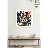 Abstract wall art with overlapping colorful leaf shapes in pink, teal, mustard, and black, framed in light wood, hanging above a wooden table with books and plants.