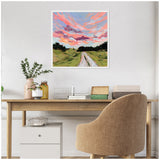 Square framed canvas by Emily Kenney depicting a vibrant sunset sky with pink and purple clouds over a green rural landscape and a white dirt path leading into the distance.