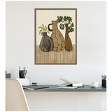 Framed canvas print depicting three stylized earthy-toned vases with abstract plants against a striped surface, hung above a modern workspace with gray desk.
