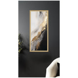 Vertical abstract wall art with flowing white, gray, black, and metallic gold brushstrokes in a light wood frame against a dark gray wall.