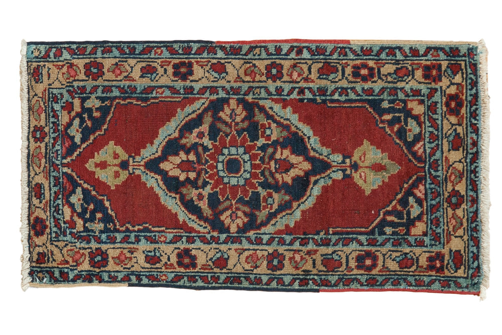 Rectangular 1.5x3 vintage Heriz rug mat with red center, navy diamond patterns, and cream floral borders, featuring fringed edges at short sides.