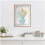 Framed canvas artwork of a blue vase with yellow flowers and green leaves, bordered by a wavy green line with bow accents against a white wall above a minimalist white shelf.