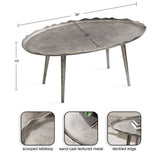 Oval metal coffee table with a scooped tabletop and textured sand-cast surface, featuring a deckled edge and four tapered legs, measuring 34 by 20 by 15 inches.