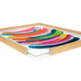Abstract framed art with vibrant curved brush strokes in pink, blue, green, and yellow on a white background, displayed in a light wood frame from an angled close-up view.