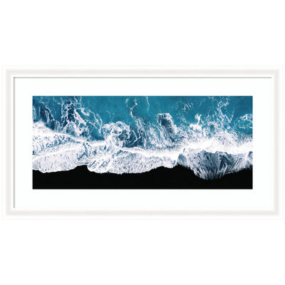 Framed minimalist art print showing aerial view of ocean waves crashing on a black beach in Iceland by Michael Schauer