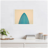 Minimalist photo of a teal surfboard tip centered on a beige background, framed in white and hanging on a white wall above a desk with plants and books.