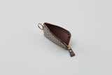 Small zipped key case with a brown and beige zigzag pattern, gold zipper and key ring, shown open on a plain light surface.
