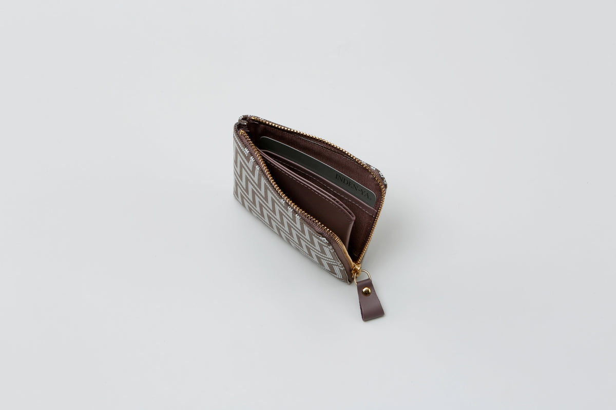 Small rectangular coin purse with brown and beige geometric pattern and a brown leather zipper pull, partially open showing multiple card slots inside.
