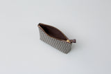 Small rectangular pouch with a brown and beige zigzag pattern and gold zipper partially open, viewed from above on a plain white background.