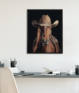 Framed portrait of a brown horse wearing a weathered tan cowboy hat and saddle, set against a black background and displayed above a minimalist desk.