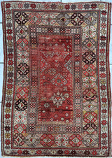 Antique Turkish hand-knotted wool prayer rug with mosque pattern in tan, gray, cream, mauve, and black on a red background, showing fringed edges and medium pile.