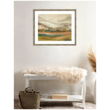 Soft-toned landscape painting with misty mountains, green and brown fields, framed in weathered gray wood, hanging above a white bench with a light fur throw
