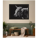 Black and white framed wall art print of a Scottish Highland cow's head with long shaggy hair and prominent horns against a dark background, hanging above a bench in a muted green and beige room.