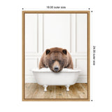 Brown bear resting with eyes closed in a white vintage clawfoot bathtub filled with bubbles against a white paneled wall and wooden floor.