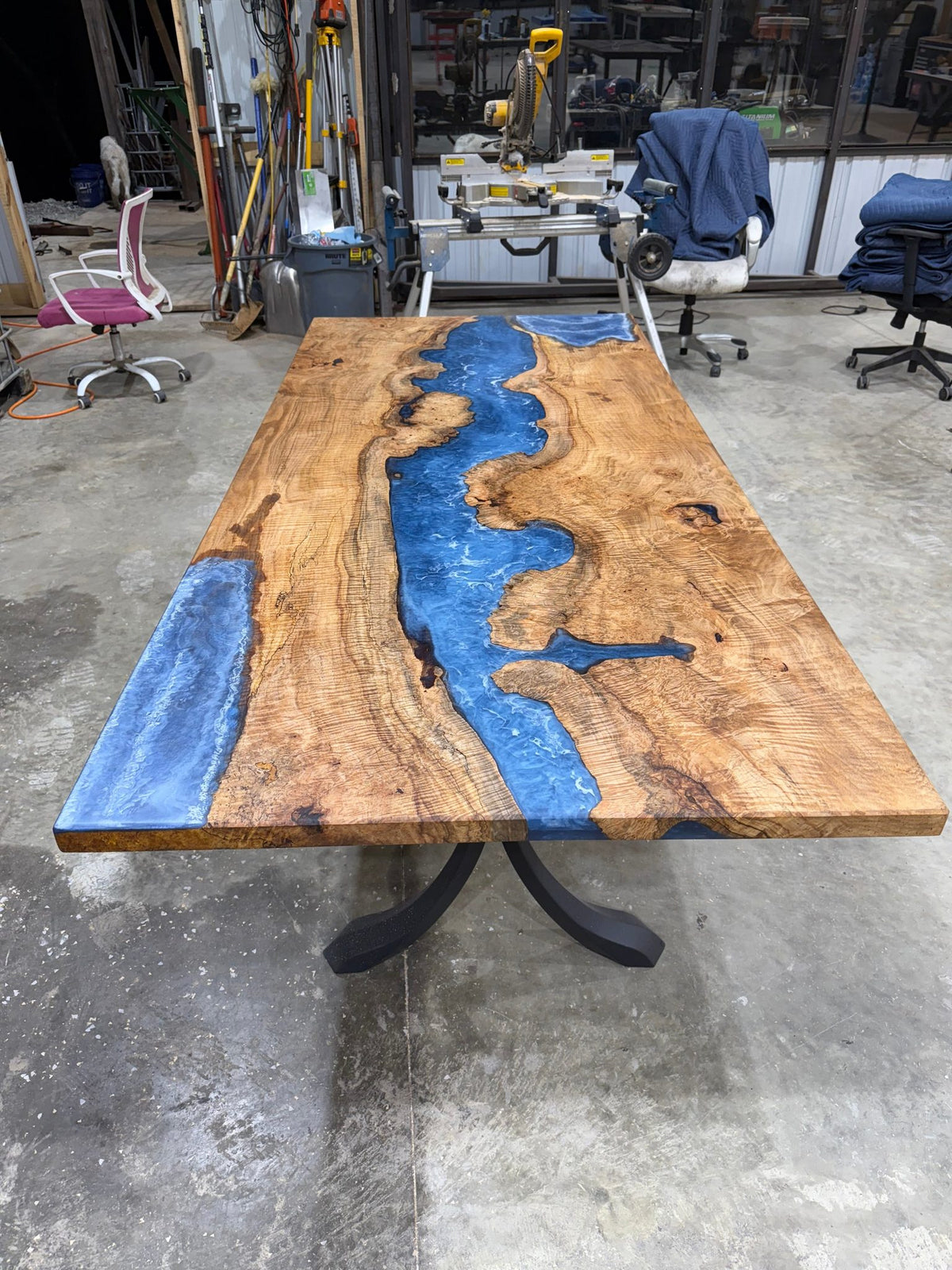 Maple Burl Epoxy River Dining Table with black steel base in a bright dining room