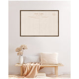 Framed beige linen fabric pinboard designed like a vintage postcard with subtle text, mounted on a white wall above a wooden bench with neutral pillows and a textured vase.