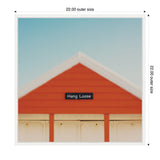 Gable of an orange wooden building with white trim under a clear blue sky, featuring a small black sign that reads 'Hang Loose'.