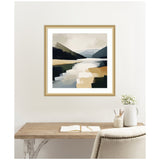 Abstract landscape painting of a mountain lake with layered blue, beige, and dark green shapes, framed in light wood and hung above a wooden desk with neutral decor.