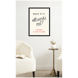 Motivational wall poster with black and red retro typography reading "What if it all works out? The best is yet to come" in a black frame above a cozy white armchair and brass side table with white vase.
