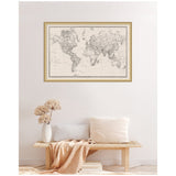 Framed black and white vintage world map with intricate details on beige background, hanging above a wooden bench with neutral cushions and a beige throw.