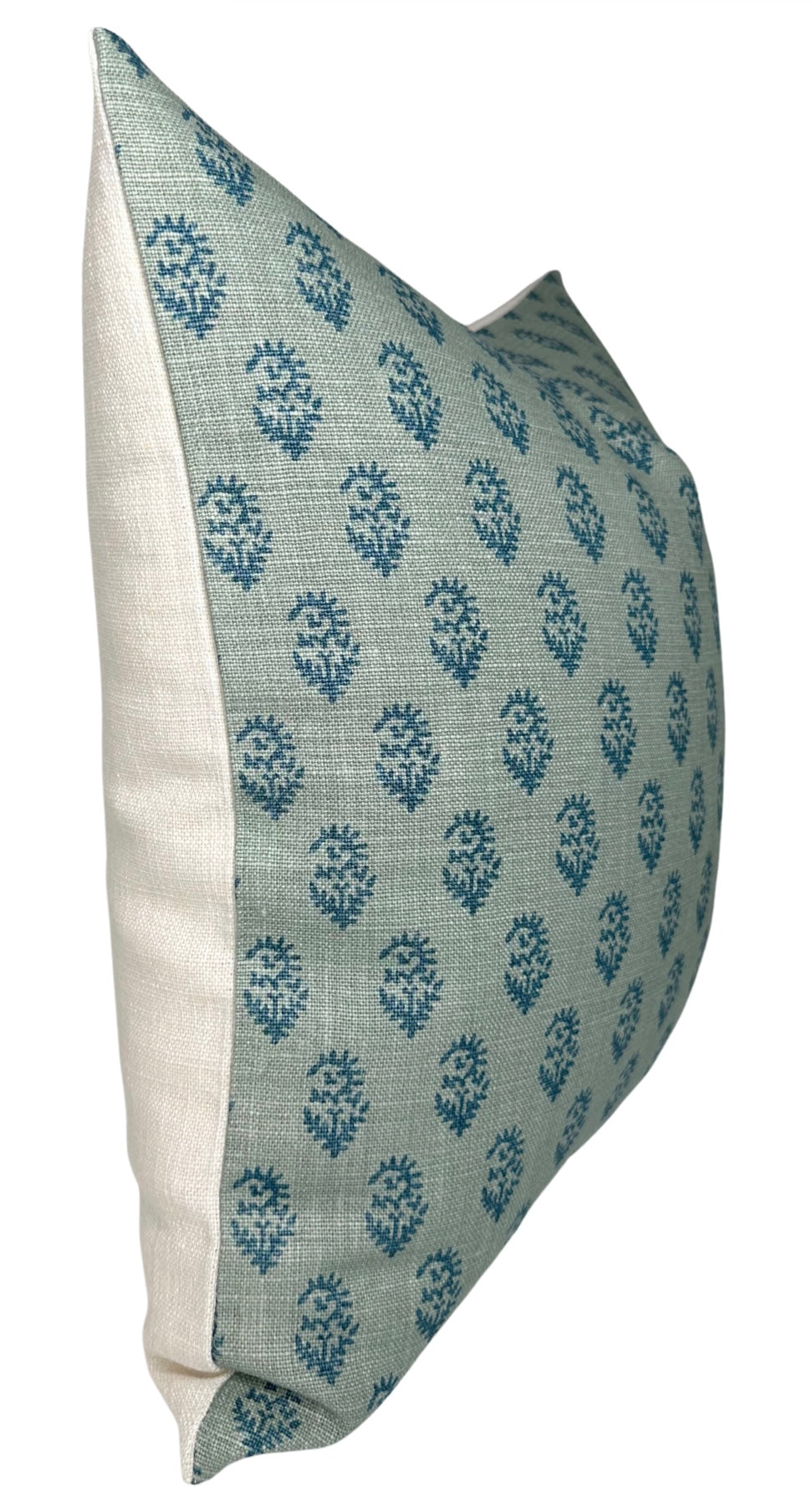 Side view of a rectangular pillow with a textured blue fabric front featuring small dark blue floral motifs and plain off-white fabric on the side panel.
