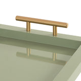 Close-up of a matte sage green rectangular tray corner with a smooth gold cylindrical handle casting a reflection on the tray surface