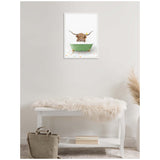 Framed canvas of a Highland cow peeking over a green bathtub, set on colorful tiled floor, hung above a white bench with a soft cream fur throw.