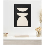 Black-framed canvas with three stacked off-white geometric shapes—a half circle, crescent, and trapezoid—against a black background, hung on a white wall above a minimalist desk.