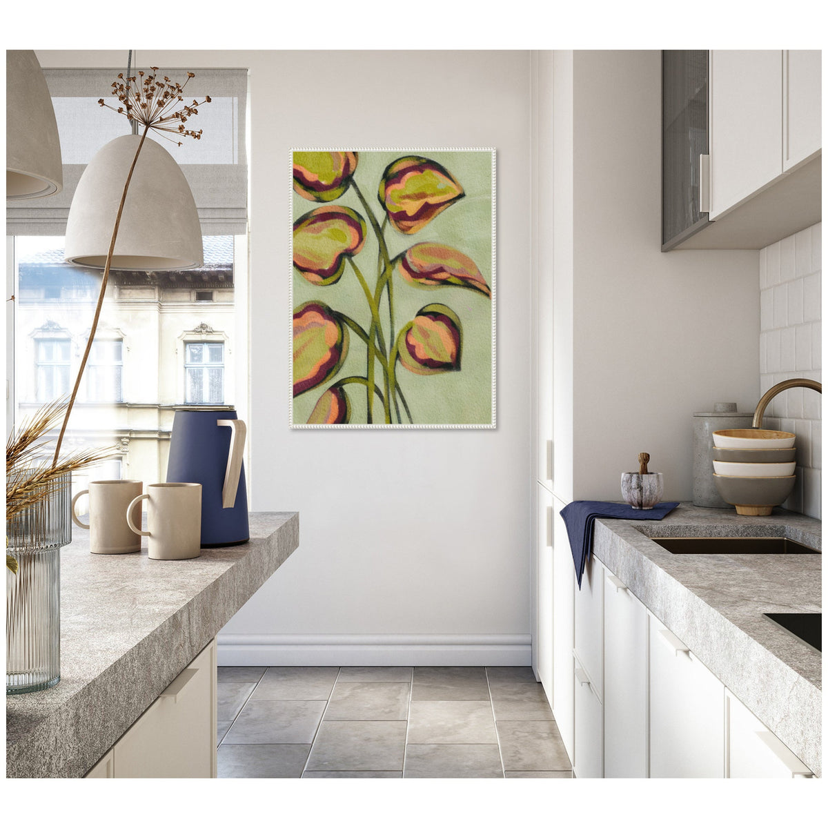 Abstract painting of green and dark pink leaves on light green background, framed and hung on a white wall in a bright kitchen with gray countertops.