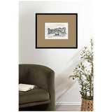 Monochrome framed sketch of a Venetian bridge and gondola, matted in tan, hanging above an olive-green armchair next to a potted plant in a woven basket.
