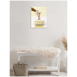 Framed canvas showing a mother and baby giraffe peeking over a pale yellow clawfoot bathtub against floral wallpaper, hanging above a white bench with a beige bag.