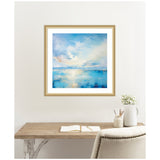 Framed painting of a tranquil coastal scene with soft blue water and sky blending with white clouds, hanging above a rustic wooden desk and chair.