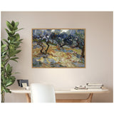 Vincent van Gogh's 'Olive Trees' framed canvas print featuring swirl-patterned olive branches and textured earth tones, hanging above a minimalist desk and plant.