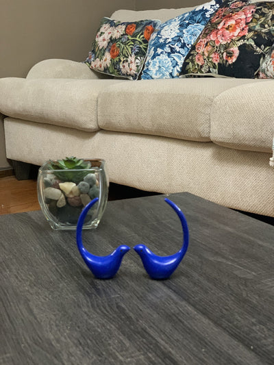 Two blue bird figurines sitting side by side on a flat surface