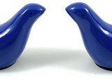 Pair of small, smooth, glossy blue bird figurines facing each other on a plain white background.