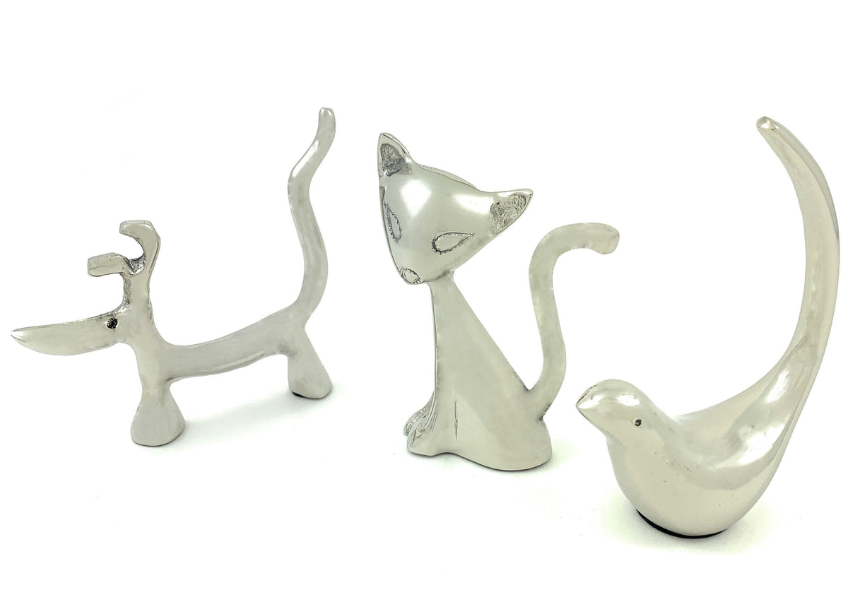 Three silver ring holders shaped like a dog with raised tail, a sitting cat with upright tail, and a bird with a tall curved tail, all smooth and shiny.
