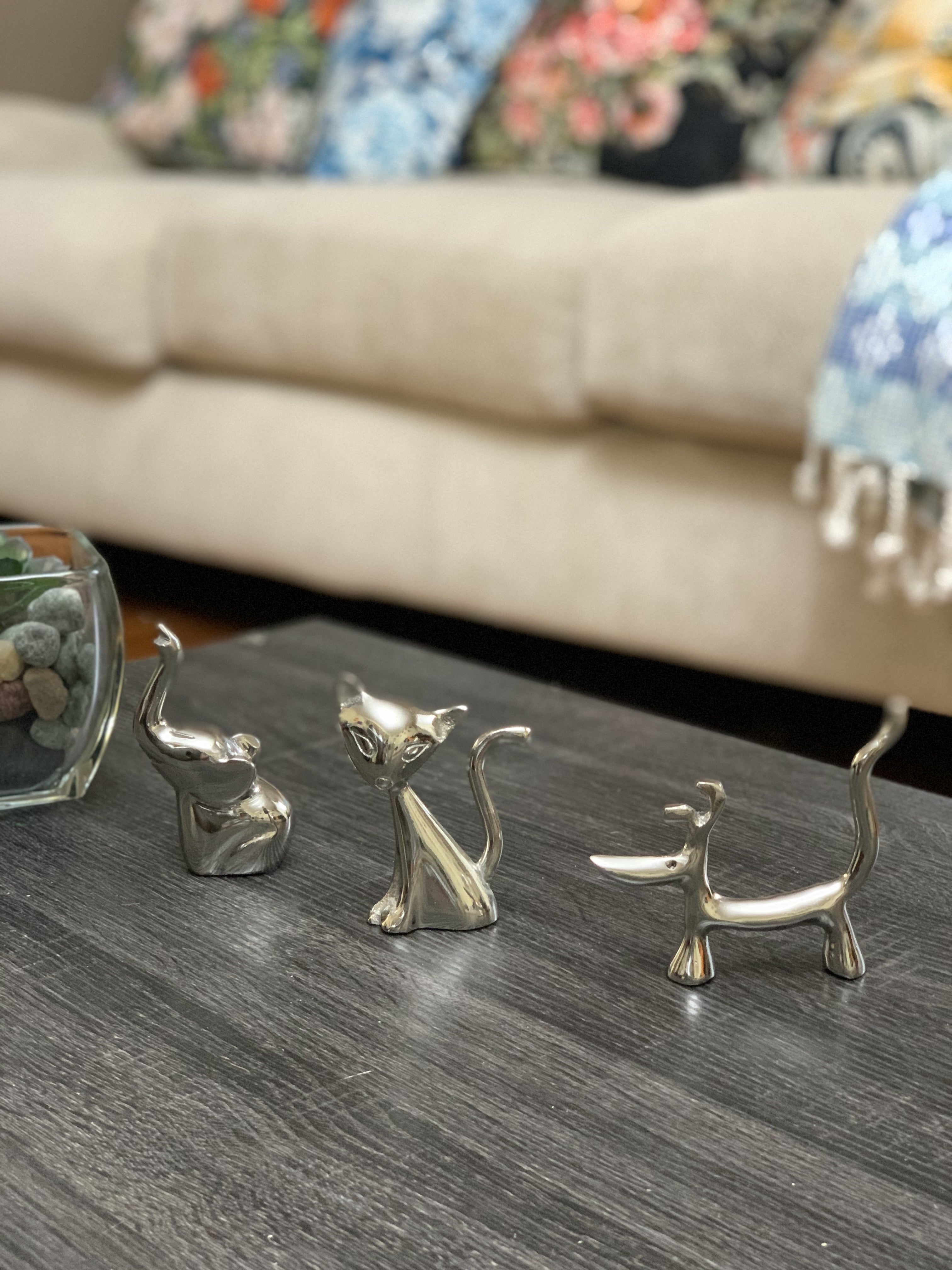 Silver dog, cat, and elephant ring holder figurines with shiny smooth surfaces displayed on a tabletop