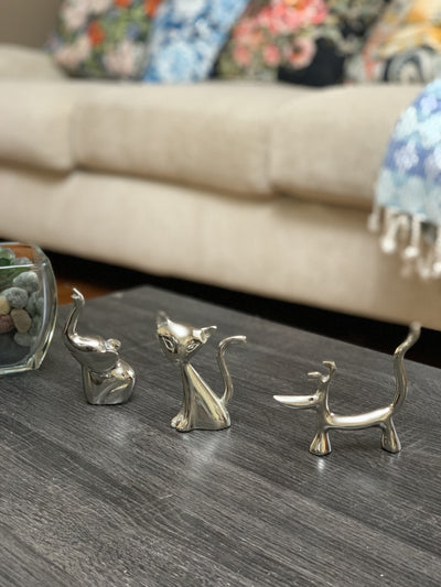 Silver dog, cat, and elephant ring holder figurines with shiny smooth surfaces displayed on a tabletop