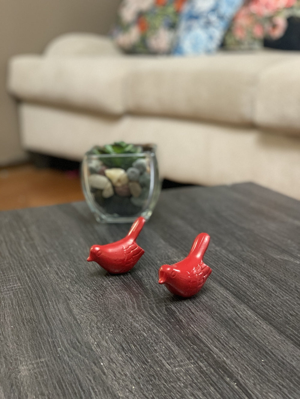 Set of two small glossy red bird figurines from Vibhsa placed on a neutral surface