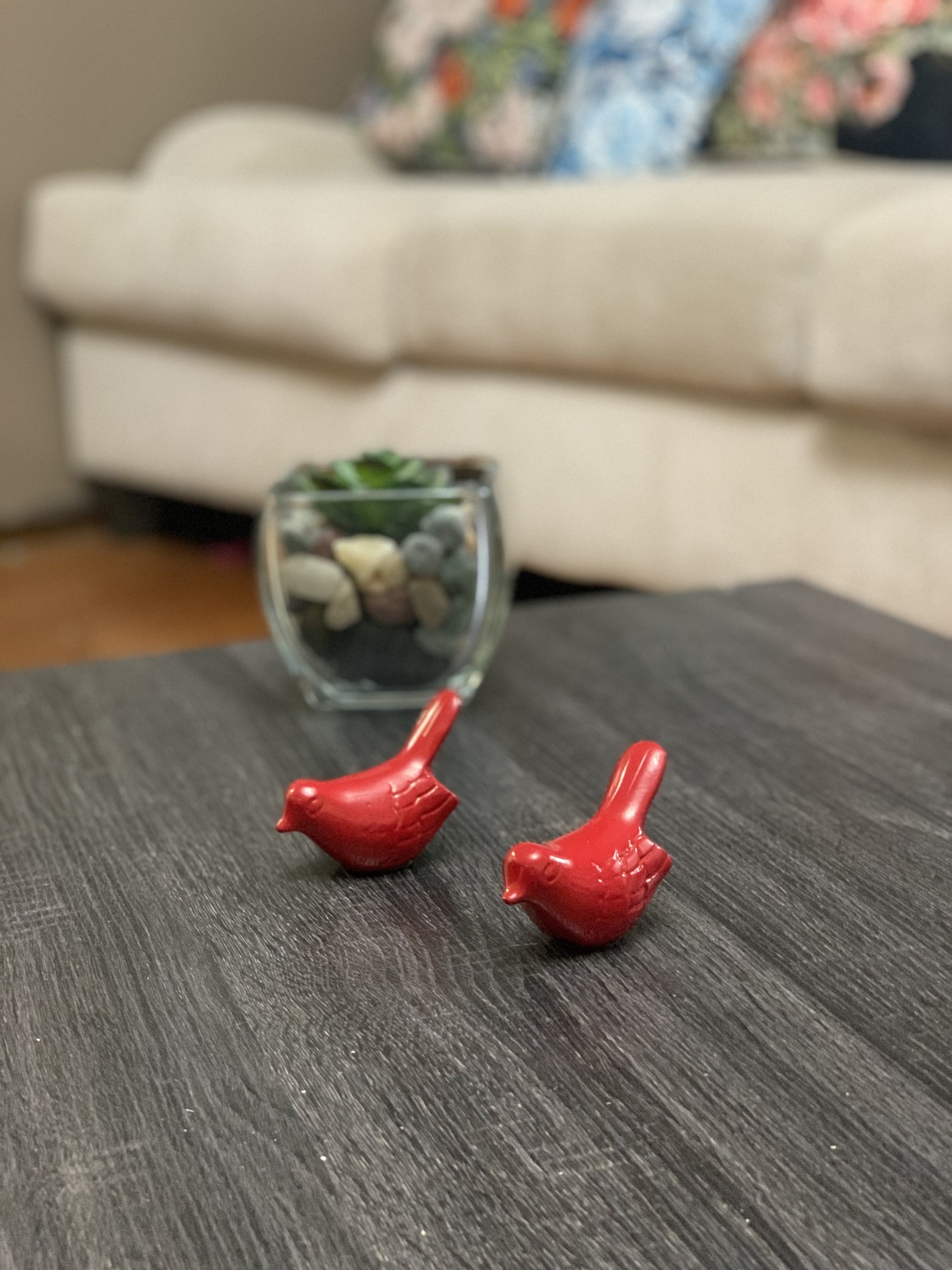 Set of two small glossy red bird figurines from Vibhsa placed on a neutral surface