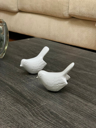 Two white bird figurines from Vibhsa with glossy finish displayed on a white wooden surface