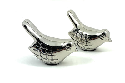 Two silver bird figurines from Vibhsa, positioned on a wooden surface.