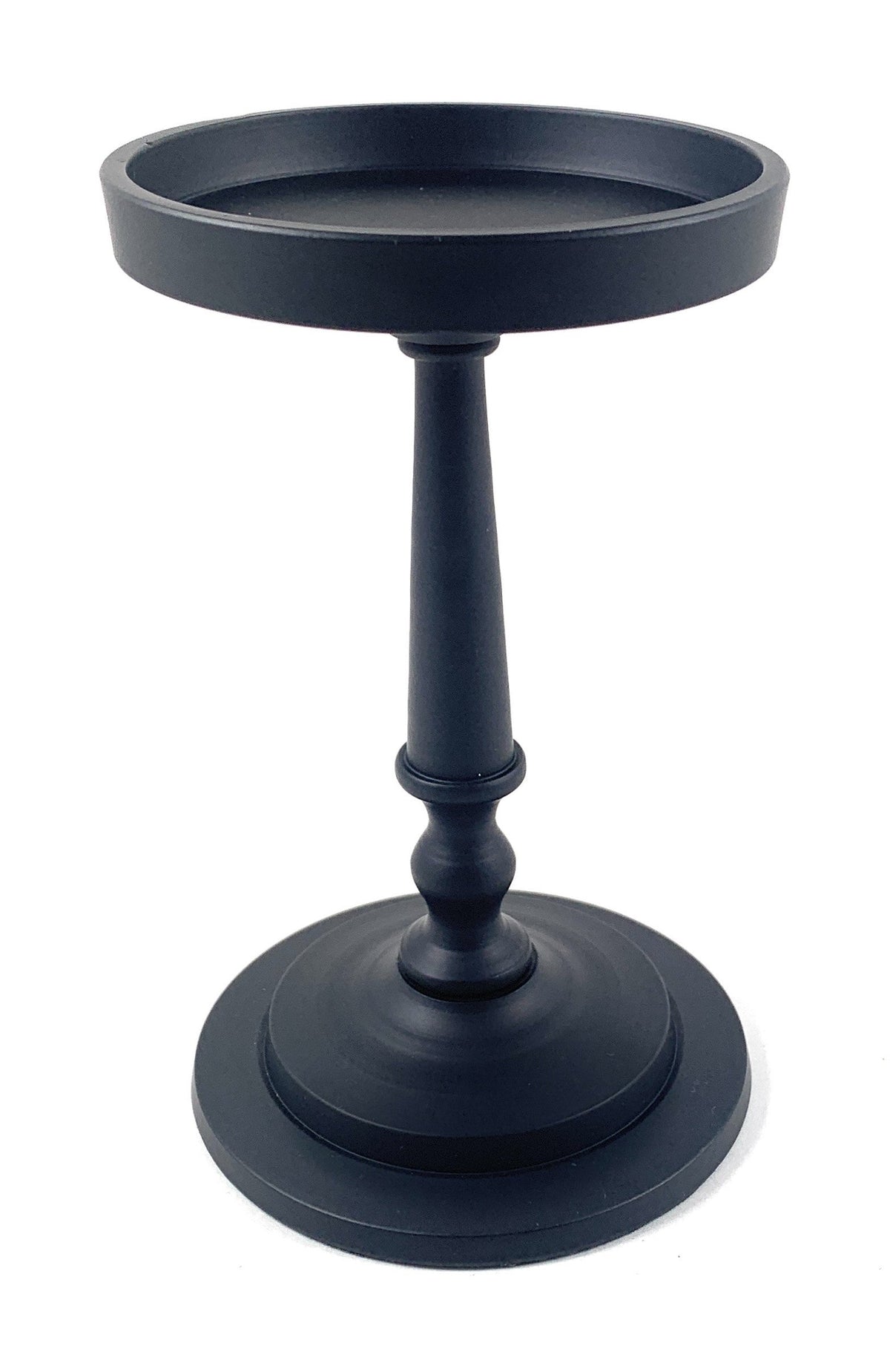 Matte black Vibhsa pillar candle holder with a round, flat tray top, slender hourglass-shaped stem, and wide circular base, standing 7 inches tall.