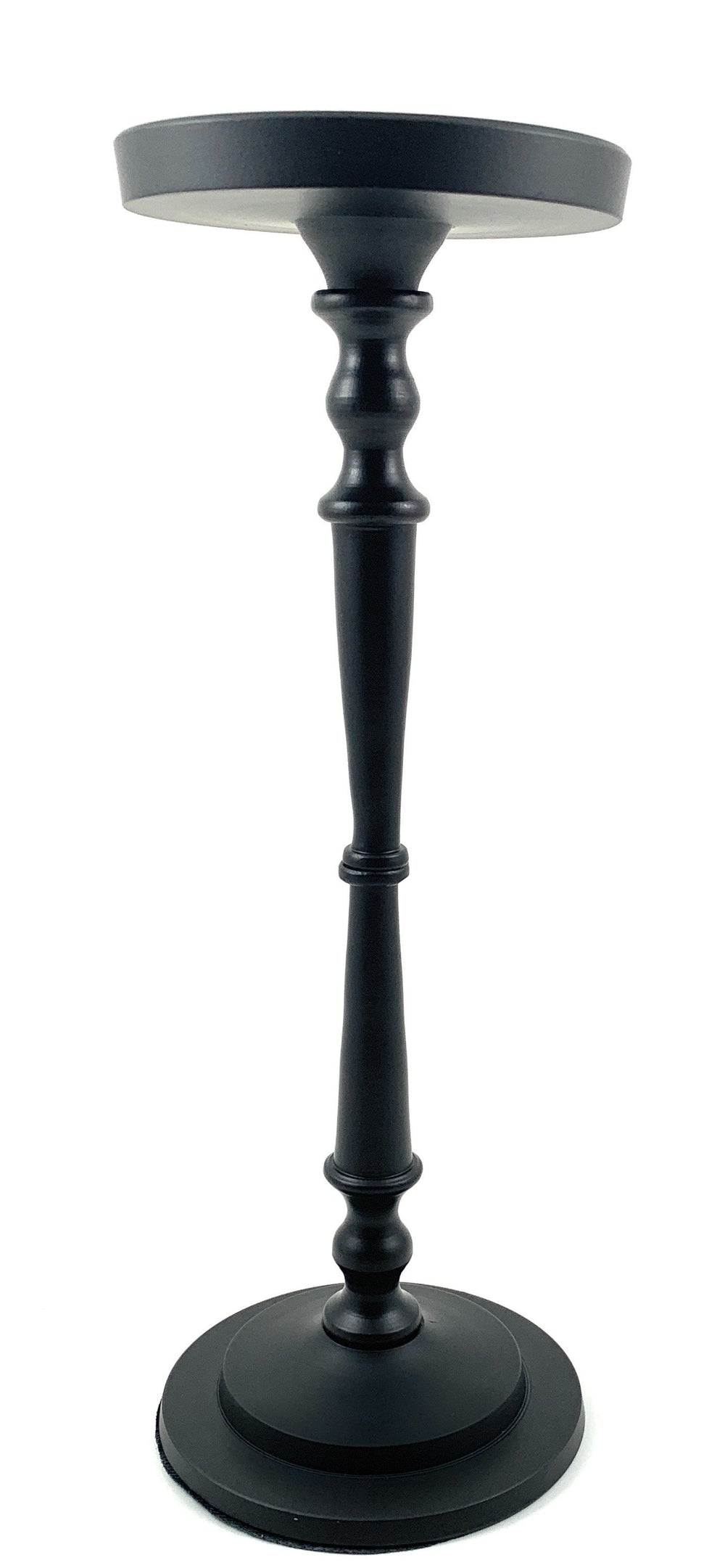 Matte black pillar candle holder by Vibhsa holding a beige candle on a warm wooden surface.