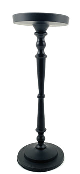 Matte black pillar candle holder by Vibhsa holding a beige candle on a warm wooden surface.