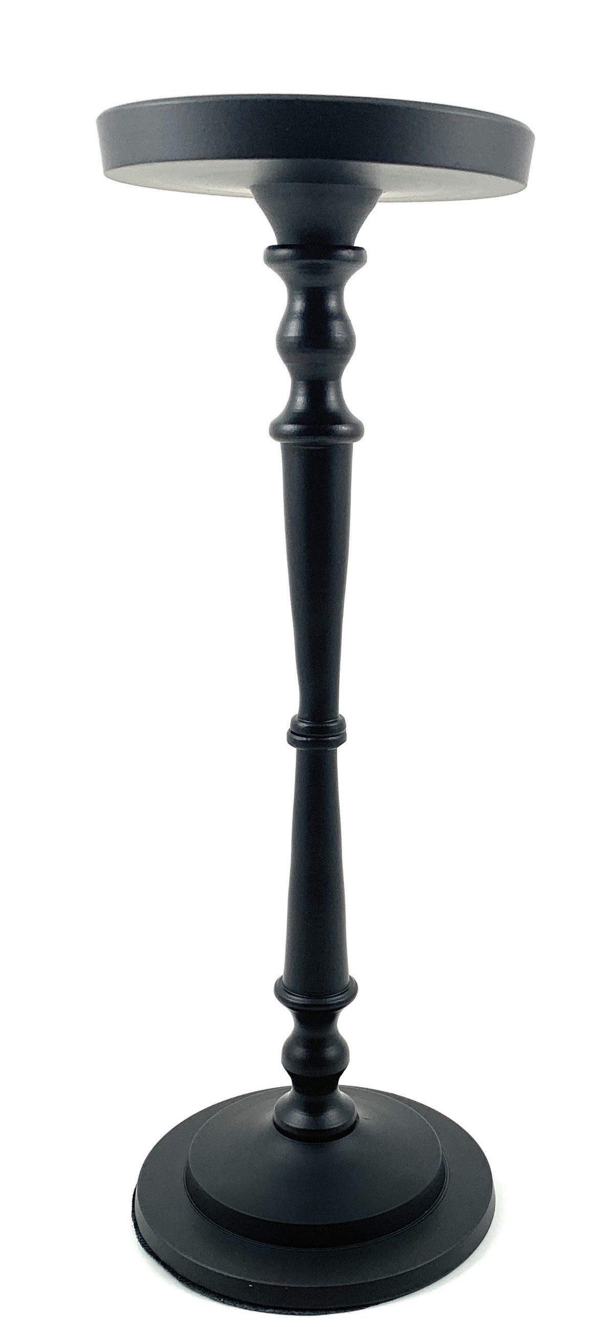 Matte black pillar candle holder by Vibhsa holding a beige candle on a warm wooden surface.