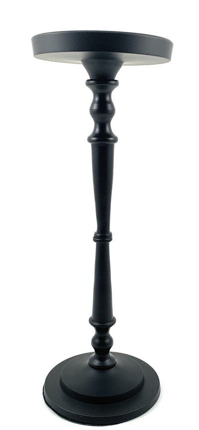 Matte black pillar candle holder by Vibhsa holding a beige candle on a warm wooden surface.