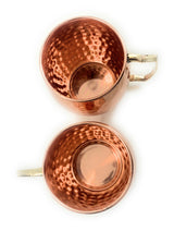 Two handcrafted copper Moscow Mule mugs with hammered texture and brass handles, shown from above on a white background.
