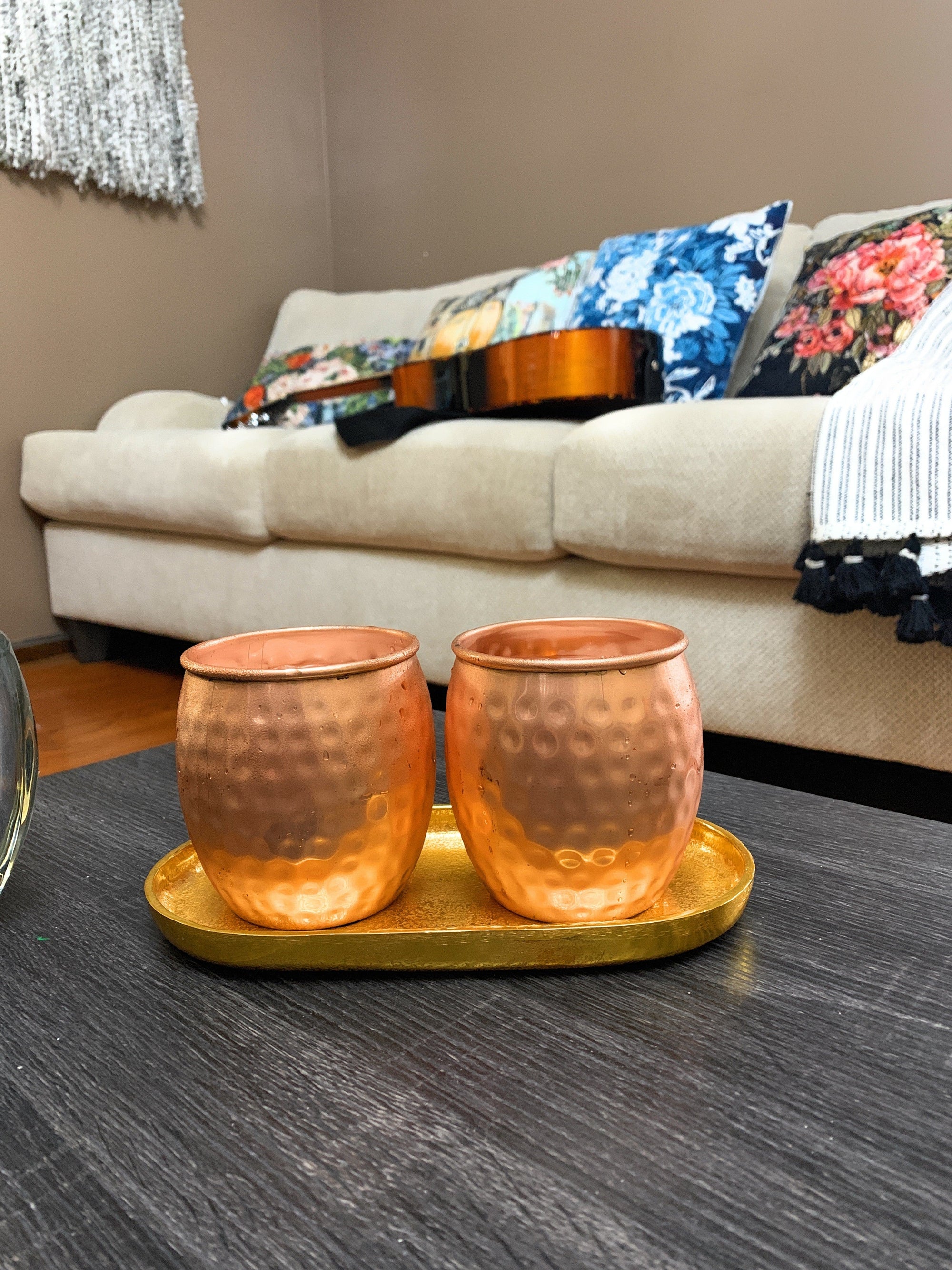 Set of four hammered copper Moscow Mule mugs with golden brass handles on a wooden surface