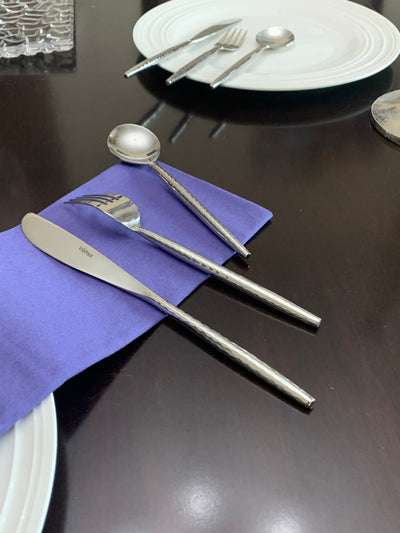 Vibhsa 36-piece silverware set laid out on a dark surface showing hammered handle detail and polished finish